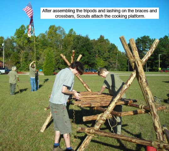 After assembling the tripods and lashing on the braces, Scouts lash on the cooking platform on a Double Tripod Chippewa Kitchen